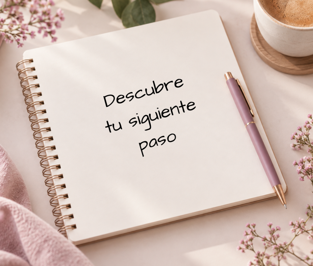 Cuaderno abierto con el mensaje «Descubre tu siguiente paso», junto a un bolígrafo malva y una taza de café.